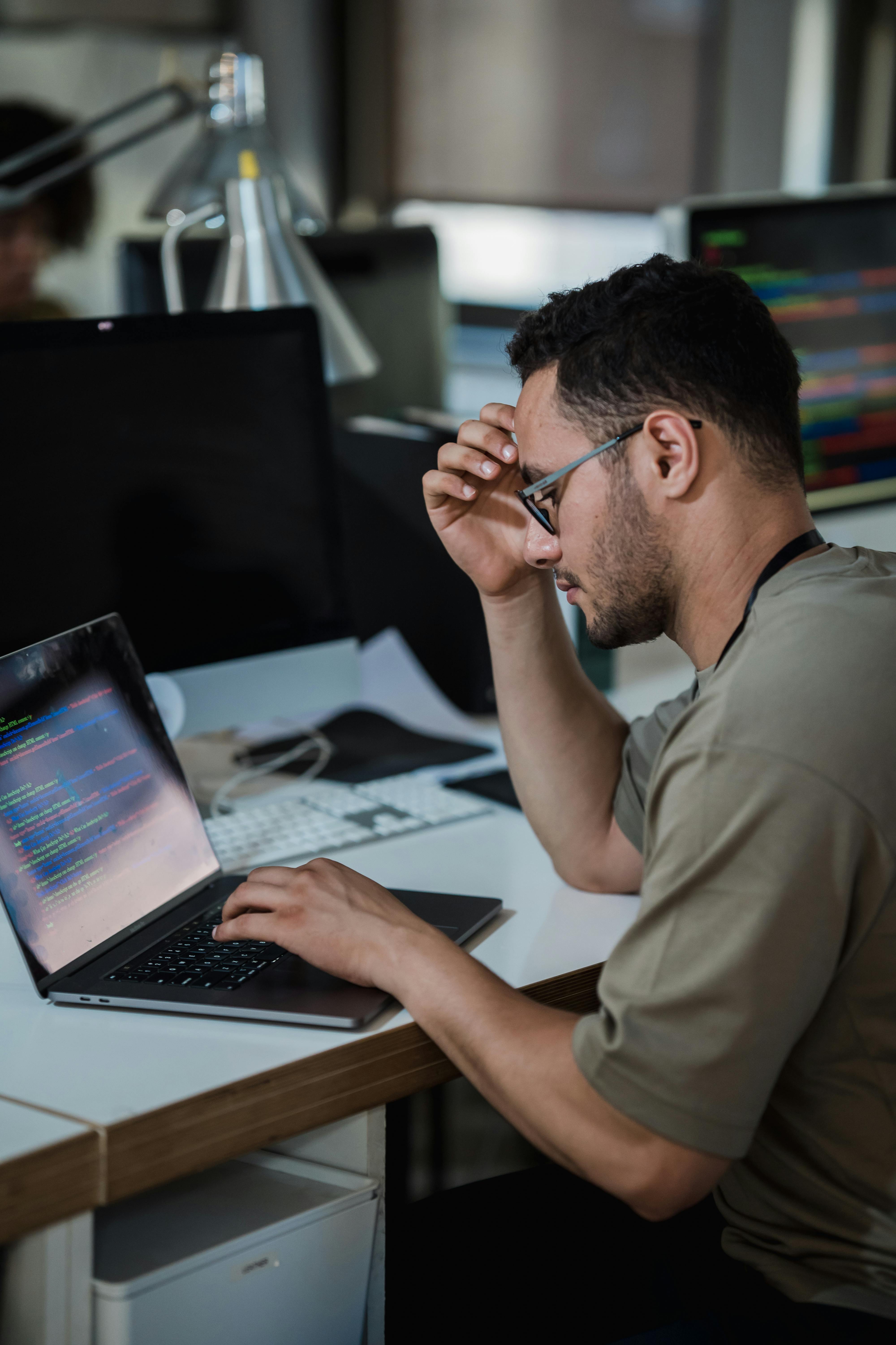 A young male software engineer is working on his computer. He appears stressed and anxious.