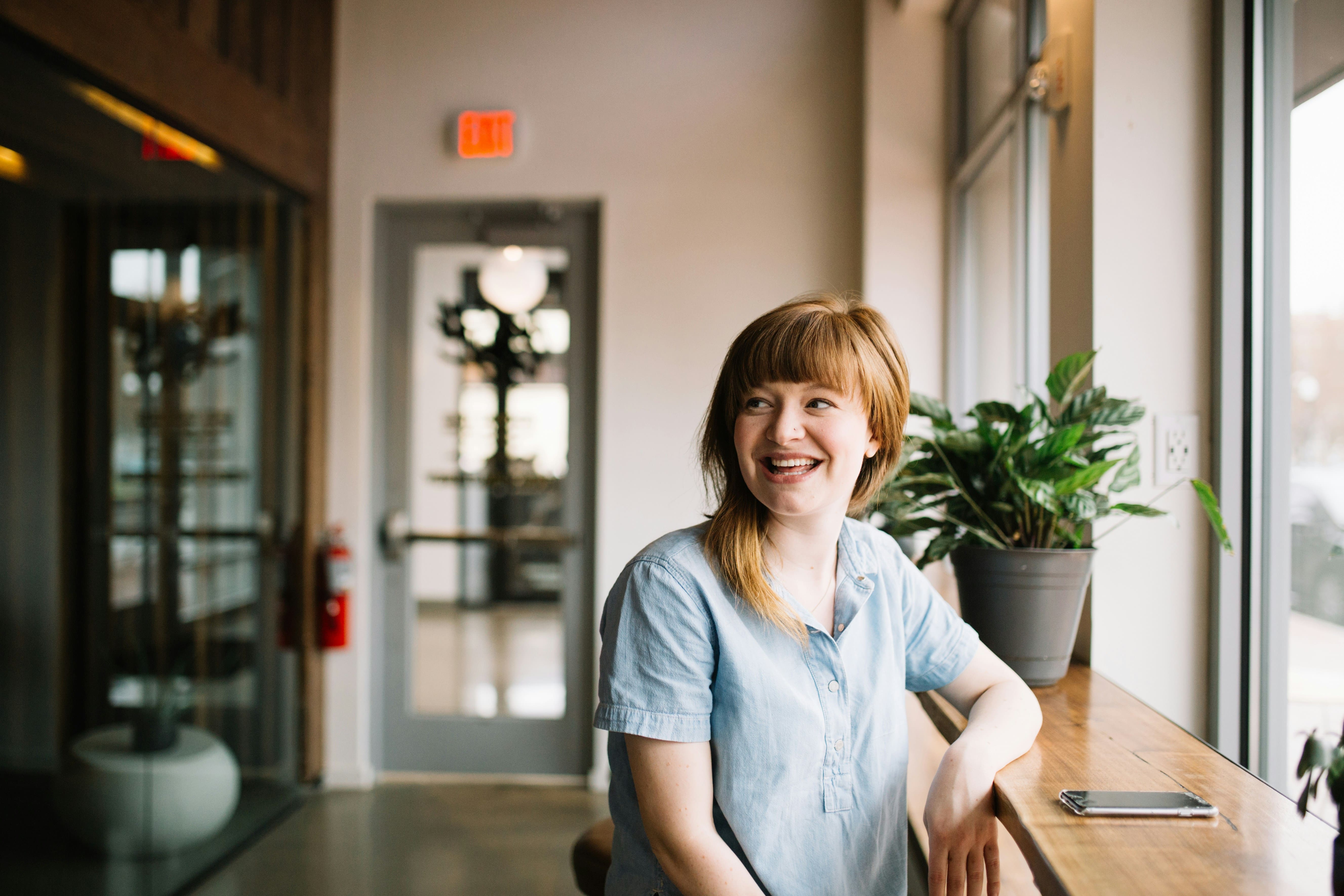 A female therapy client is dressed in casual clothing and is smiling and happy at her workplace.